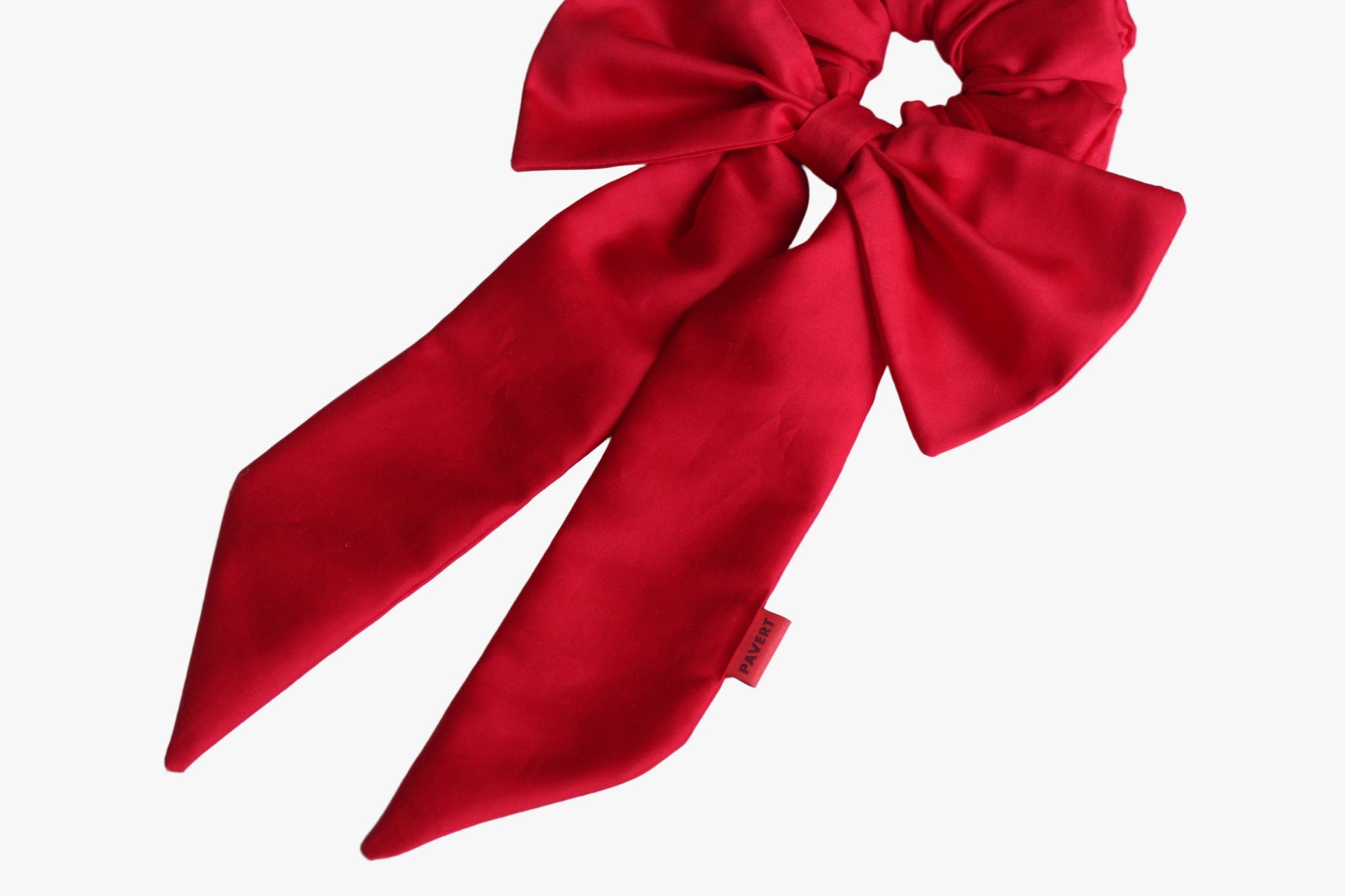 Red bow-shaped hair scrunchie on a light blue background